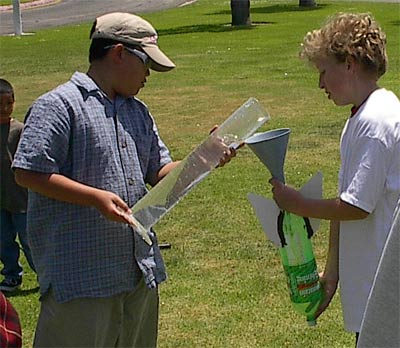 Using a graduated cylinder to load a precise amount of water into a bottle rocket.